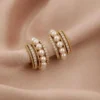 Golden hoop earrings with pearls and sparkling stones on soft beige fabric