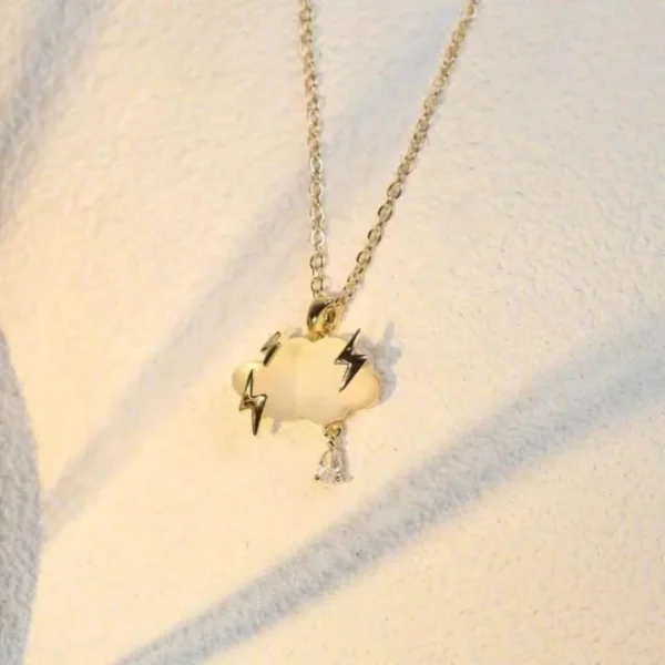 Gold chain necklace with a matte cloud pendant, gold lightning bolts, and a crystal raindrop charm.
