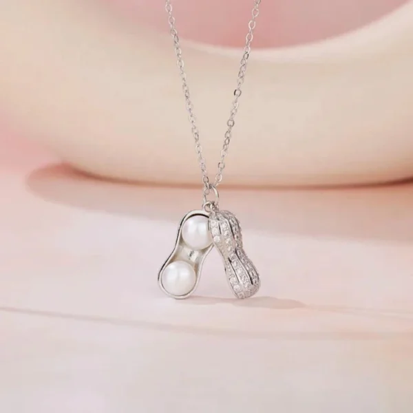 Silver necklace with a peanut-shaped pendant featuring twin pearls inside a textured metallic shell design
