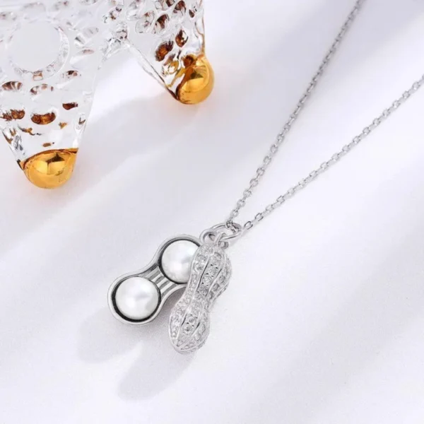 Silver necklace with a peanut-shaped pendant featuring twin pearls inside a textured metallic shell design