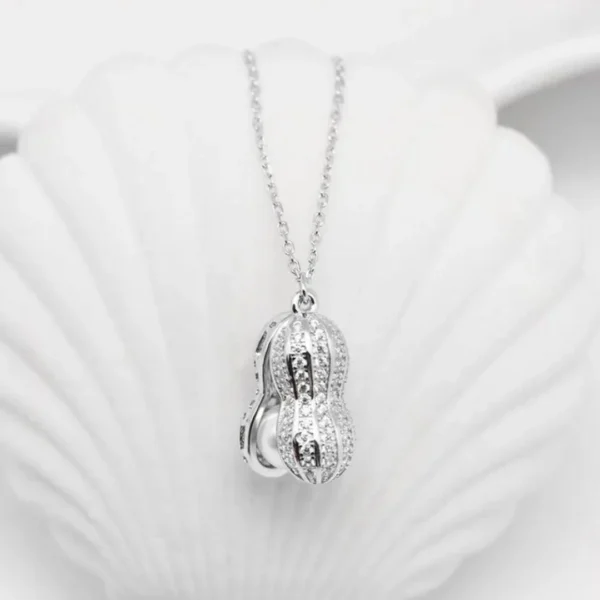 Silver necklace with a peanut-shaped pendant featuring twin pearls inside a textured metallic shell design