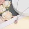 Elegant pink gemstone pendant necklace with silver chain, styled on a flatlay with roses.