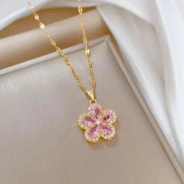 Gold chain necklace with a pink flower-shaped pendant made of teardrop crystals and surrounded by tiny white stones