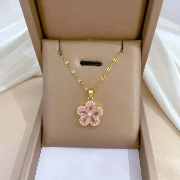 Gold chain necklace with a pink flower-shaped pendant made of teardrop crystals and surrounded by tiny white stones