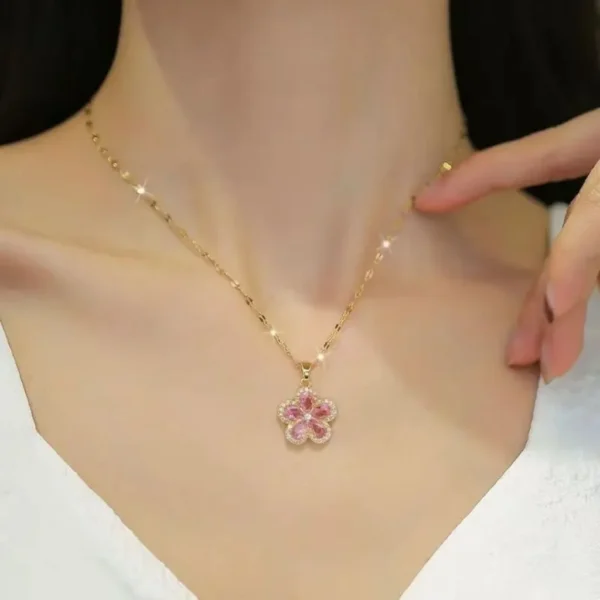 Gold chain necklace with a pink flower-shaped pendant made of teardrop crystals and surrounded by tiny white stones