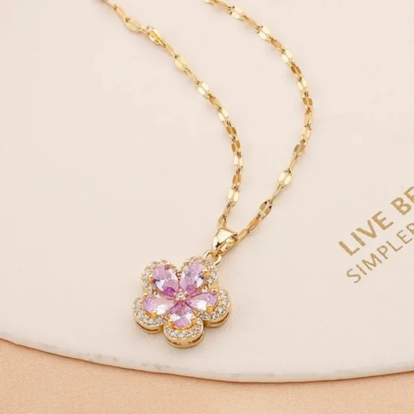 Gold chain necklace with a pink flower-shaped pendant made of teardrop crystals and surrounded by tiny white stones
