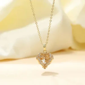 Gold chain necklace with a heart-shaped pendant featuring a large center crystal and surrounded by small white stones