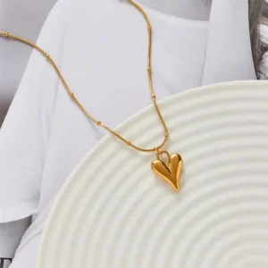 Trendy gold necklace with a smooth puffed heart-shaped pendant on a textured gold chain, perfect for everyday chic style.