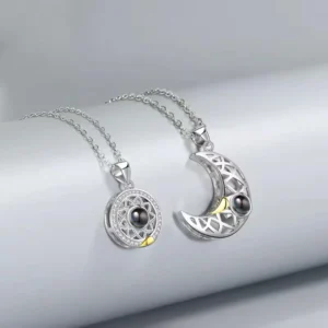 Silver couple necklace set with sun and moon themed pendants, featuring celestial cutouts and black pearls, perfect for matching jewelry.