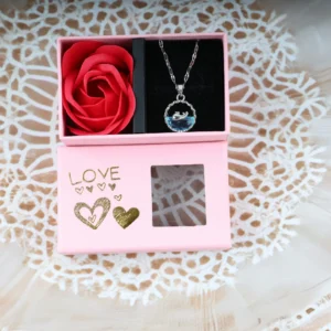 Romantic dolphin necklace with blue crystal in a pink love gift box and red rose.