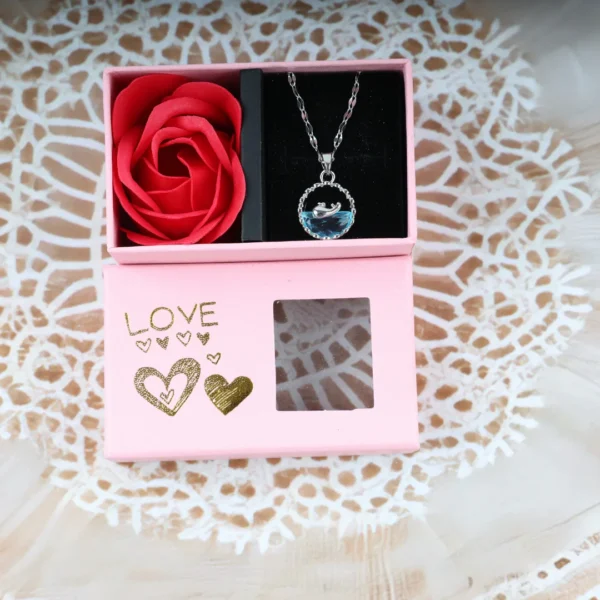 Romantic dolphin necklace with blue crystal in a pink love gift box and red rose.