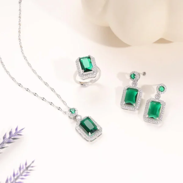 Glamorous green gemstone jewelry set with emerald-style stones in silver-tone setting, includes necklace, ring, and earrings.