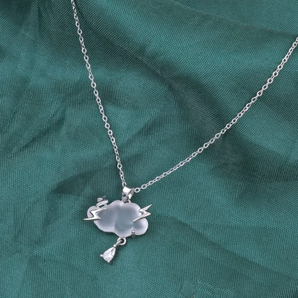 Gold chain necklace featuring a frosted white cloud pendant with lightning bolt details and a teardrop charm, styled with natural stones and wood.