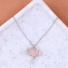 Silver chain necklace with a light pink cloud-shaped pendant, lightning bolt accents, and a teardrop crystal charm, displayed on a terrazzo-style surface.