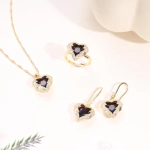 Gold jewelry set with deep purple heart-shaped crystals, including a necklace, earrings, and ring, surrounded by sparkling stones.