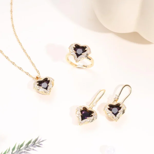 Gold jewelry set with deep purple heart-shaped crystals, including a necklace, earrings, and ring, surrounded by sparkling stones.