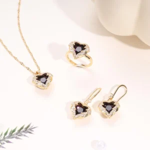 Gold jewelry set with deep purple heart-shaped crystals, including a necklace, earrings, and ring, surrounded by sparkling stones.